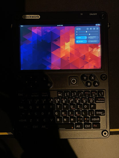 Photo of a ClockworkPi uConsole with GNOME desktop environment. It has a blue and red wallpaper and the upper control panel open.