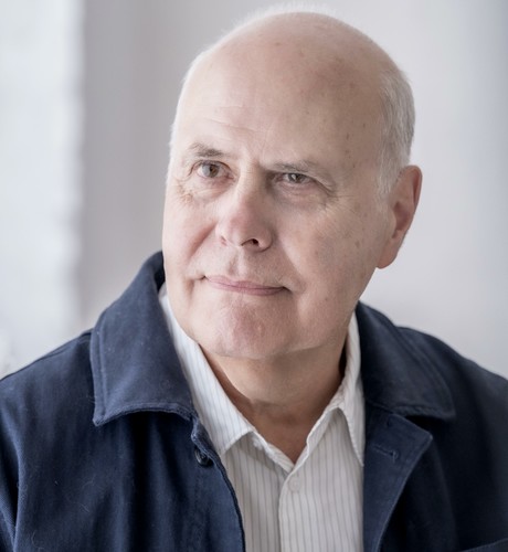 Colour Photograph of British composer Adam Pounds - a white 70 year old man wearing a navy jacket and a white with thin grey stripes shirt. The man is looking to the left, smiling and looking pensive. Colour Photograph of British composer Adam Pounds - a white 70 year old man wearing a navy jacket and a white with thin grey stripes shirt. The man is looking to the left, smiling and looking pensive.