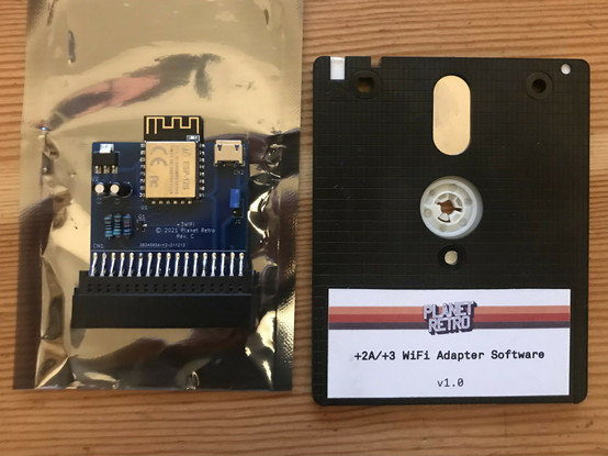 Small blue PCB with ESP WiFi module next to a 3" Amstrad disk