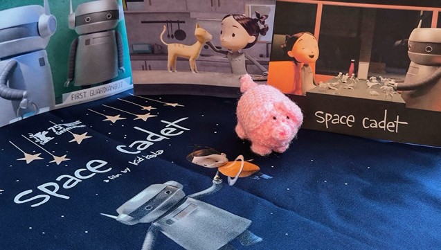 Ein haekelschwein umgeben von Motiven aus dem Animationsfilm "Space Cadet": ein Roboter, eine Katze und ein Mädchen.