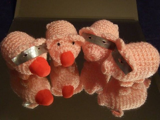 Vier Häkelnschweine, davon zwei mit roter Nase und drei mit Augenmasken.