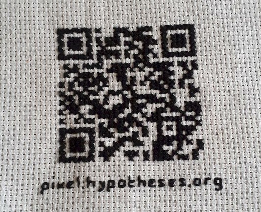 cross-stitch embroidery showing a qr code. written below is the encoded website address "pixel.hypotheses.org"