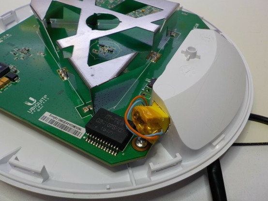 Inside the dish, a square PCB with a weirdly shaped antenna. A barrel jack connector has been stuff in at an angle into a hand-made cut into the plastic, with wires going to the PCB.