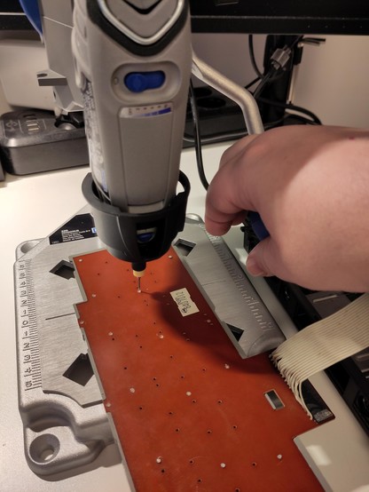 Drilling the case plastic rivets out via the keyboard PCB for alignment, and creating screw holes.

(Reenactment. It's recommended to hold the piece down with the other hand instead.)