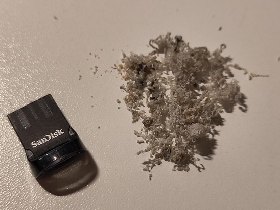 Cheap keyboard "smoke" or rather, very fine chips and dust, as result of the drilling process. SanDisk USB thumb drive for scale.