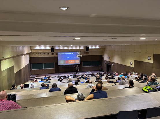 Picture of the room D2 at the Faculty of Electrical Engineering and Computing (FER) in Zagreb, Croatia. Shot from the back to the stage with lots of people in seats.