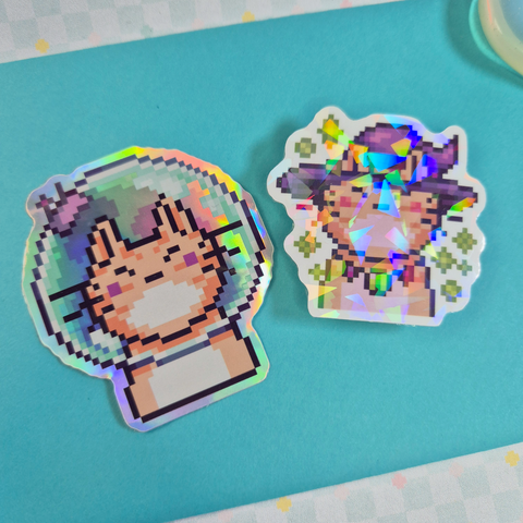 photo of holographic Vinyl Sticker with Pixel Art Astro Cat and Witch Cat motive