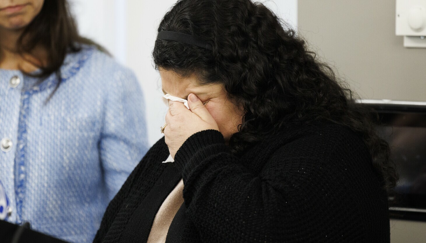 Yolanda Orozco sits and covers her face while crying during a news conference.