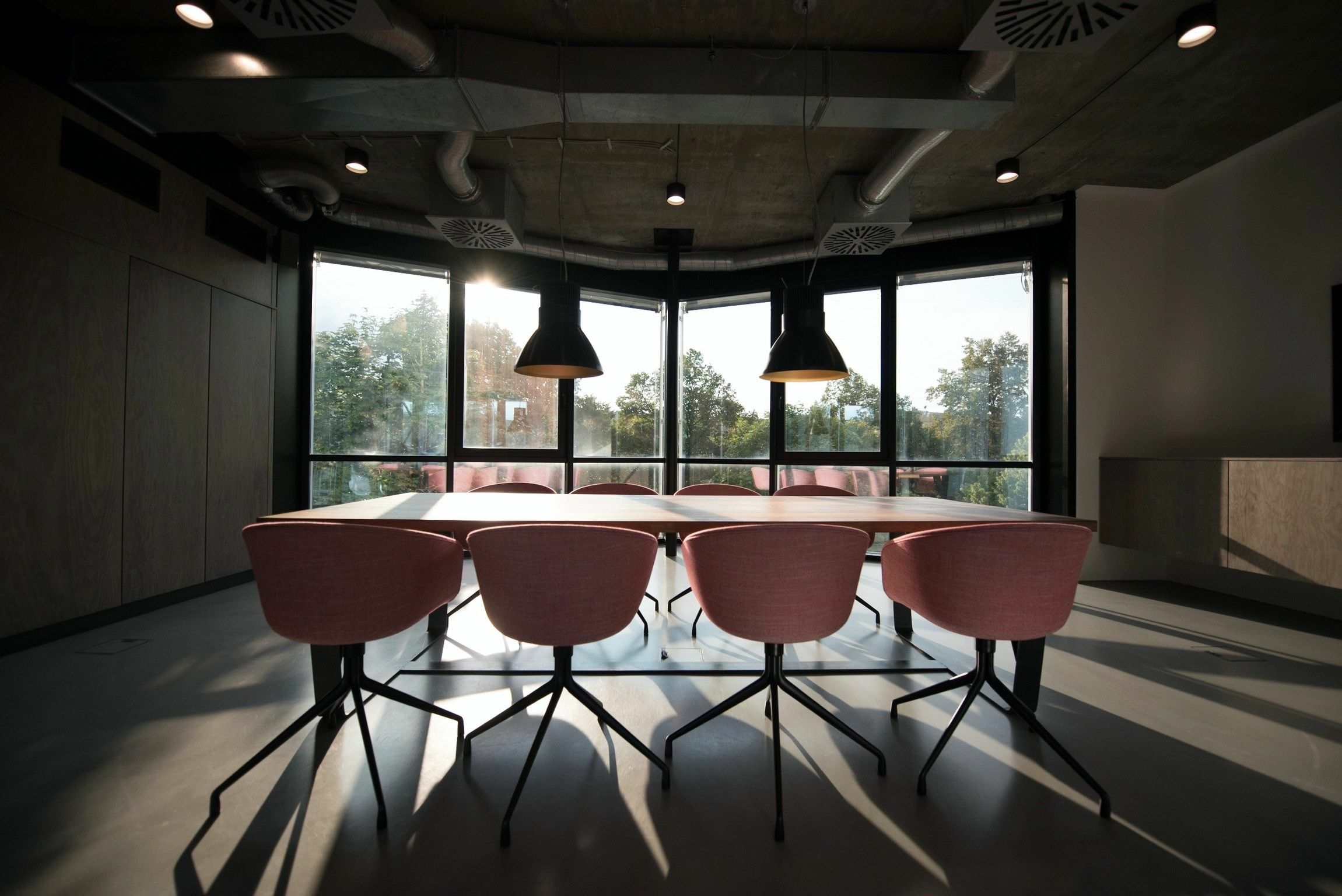 A table surrounded by eight empty chairs. (Nastuh Abootalebi/Unsplash)