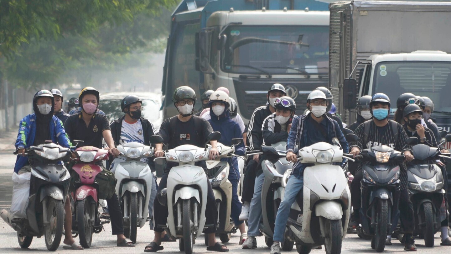 People wearing face masks wait at a traffic signal in Hanoi, Vietnam, on Nov. 14, 2024. (AP Photo/Hau Dinh)