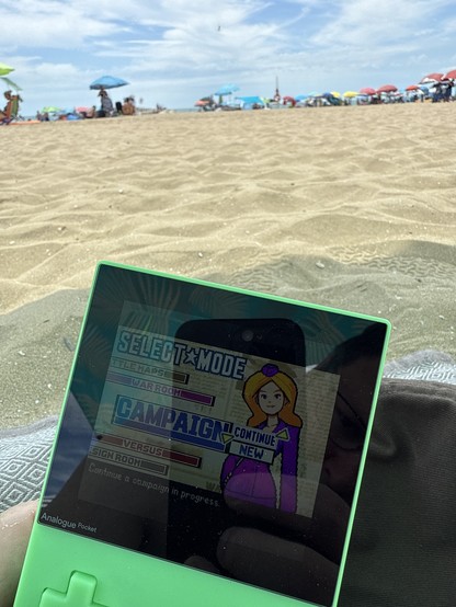 An Analogue Pocket playing Advance Wars 2 on a beach. 